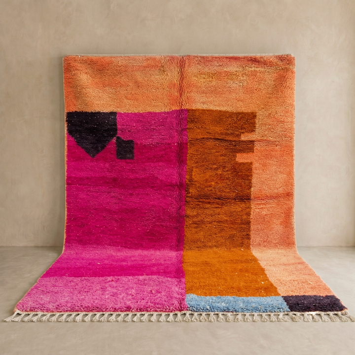 Handwoven Moroccan wool rug in magenta pink and burnt orange color blocks with black and blue accents, fringed ends