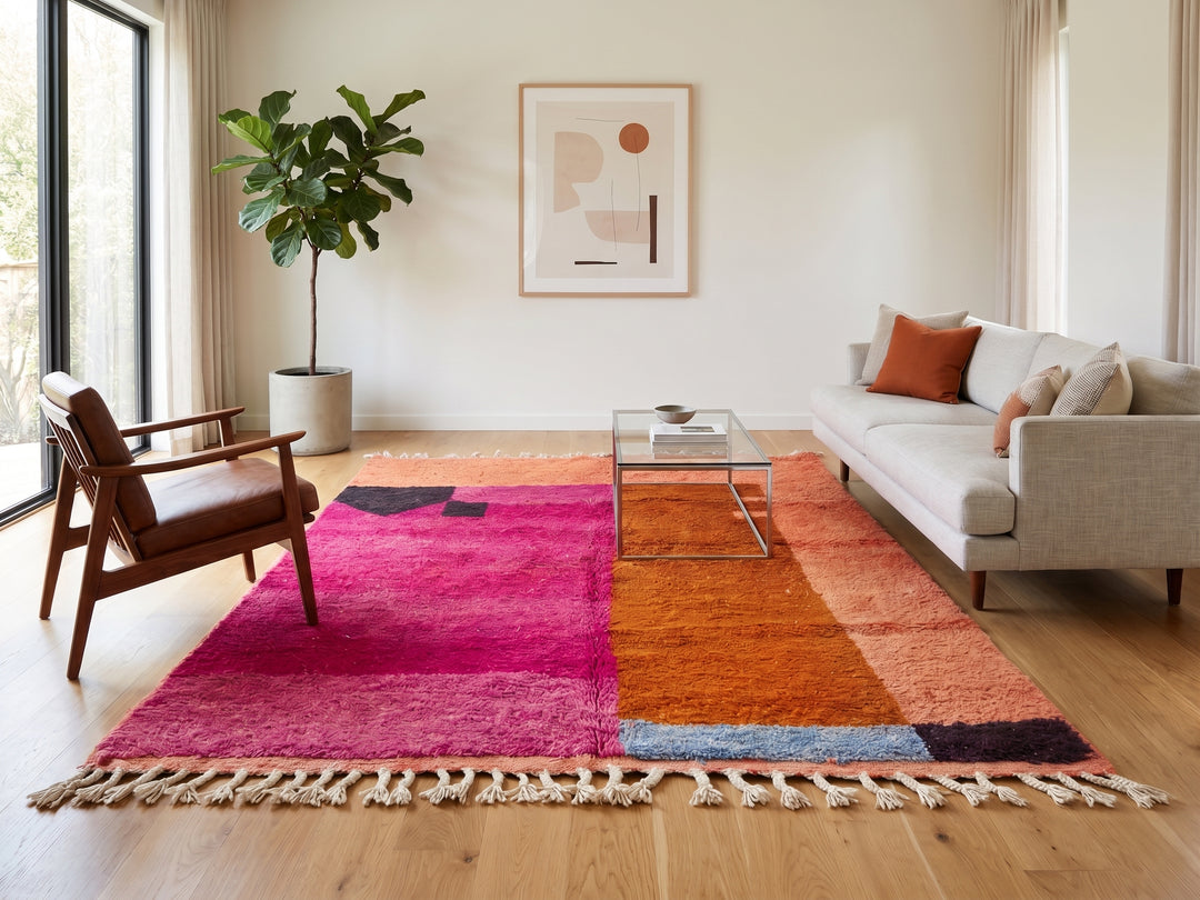 Handwoven Moroccan wool rug in magenta pink and burnt orange color blocks with black and blue accents, fringed ends