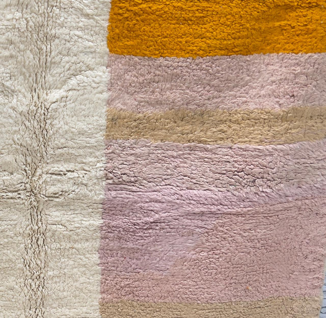 Round Moroccan wool rug with soft geometric blocks in green, pink, beige, brown, and orange.