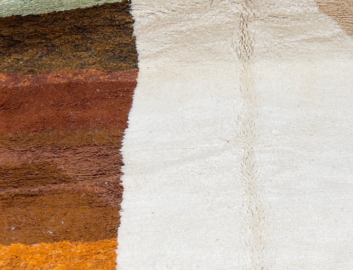 Round Moroccan wool rug with soft geometric blocks in green, pink, beige, brown, and orange.