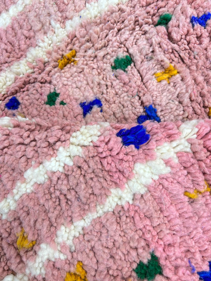 Bright pink round Moroccan wool rug with colorful dotted accents, white abstract lines, and rose and blue contrast sections.