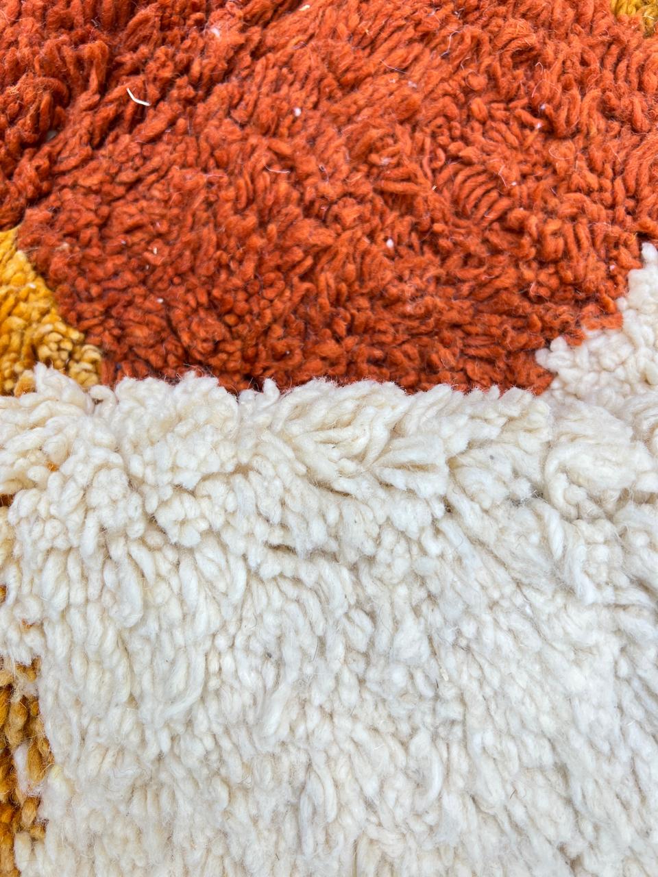 White round Moroccan wool rug with bold stacked geometric color segments in navy blue, teal, pink, terracotta, and orange.