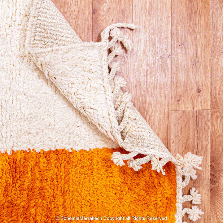 Handwoven Moroccan rug in orange, red, and white color blocks with symbolic Berber motif and soft wool texture