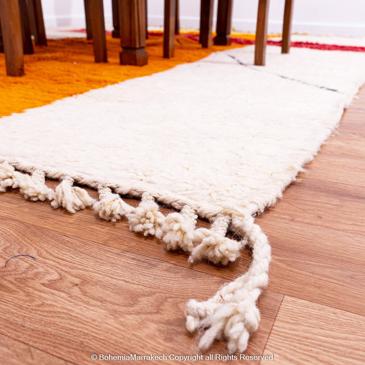 Handwoven Moroccan rug in orange, red, and white color blocks with symbolic Berber motif and soft wool texture