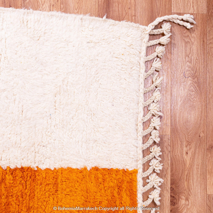Handwoven Moroccan rug in orange, red, and white color blocks with symbolic Berber motif and soft wool texture