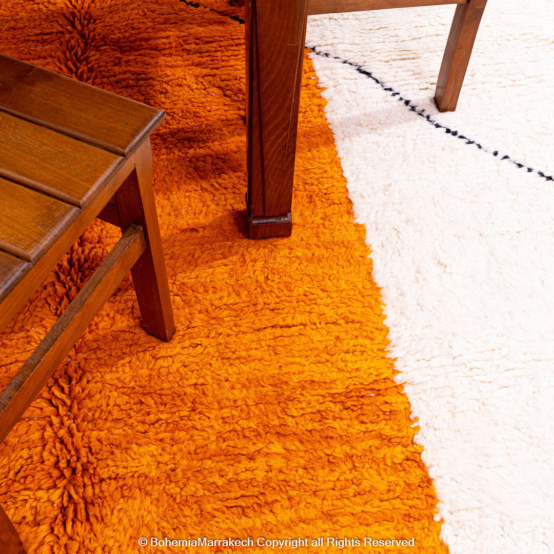 Handwoven Moroccan rug in orange, red, and white color blocks with symbolic Berber motif and soft wool texture