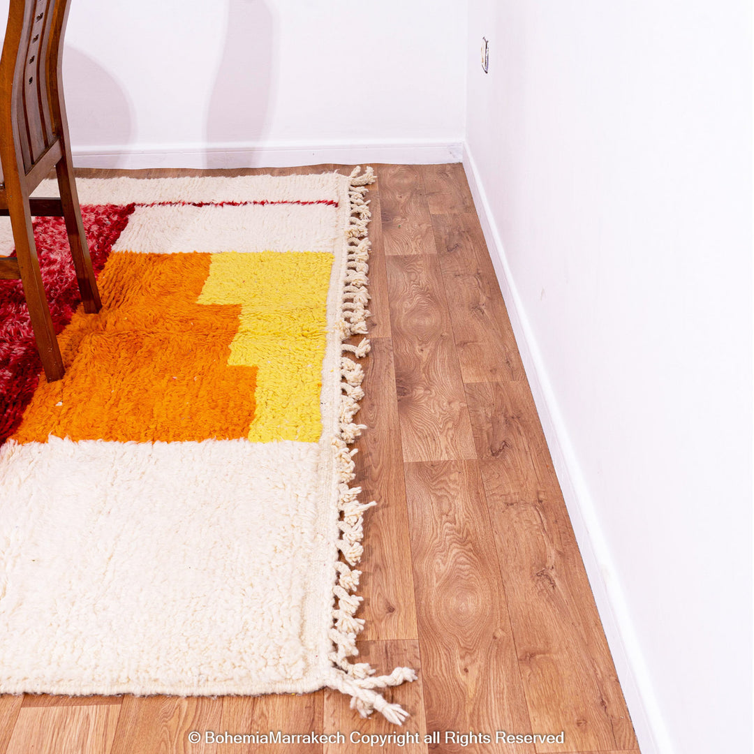 Handwoven Moroccan rug in orange, red, and white color blocks with symbolic Berber motif and soft wool texture