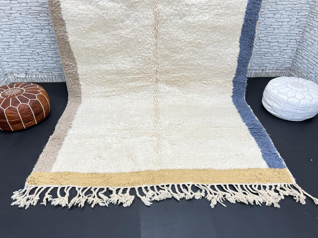 Handwoven neutral Moroccan wool rug with minimalist beige, mustard, and blue borders