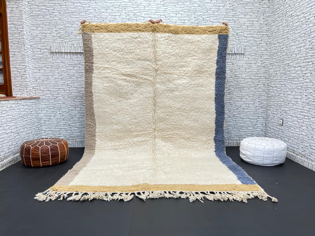 Handwoven neutral Moroccan wool rug with minimalist beige, mustard, and blue borders