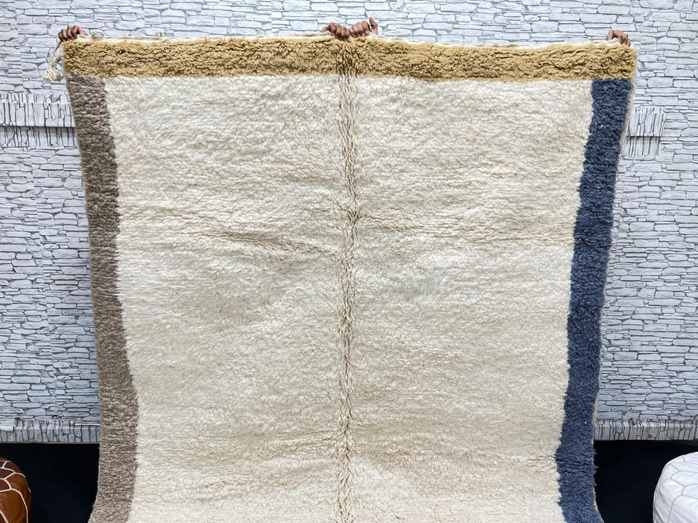 Handwoven neutral Moroccan wool rug with minimalist beige, mustard, and blue borders