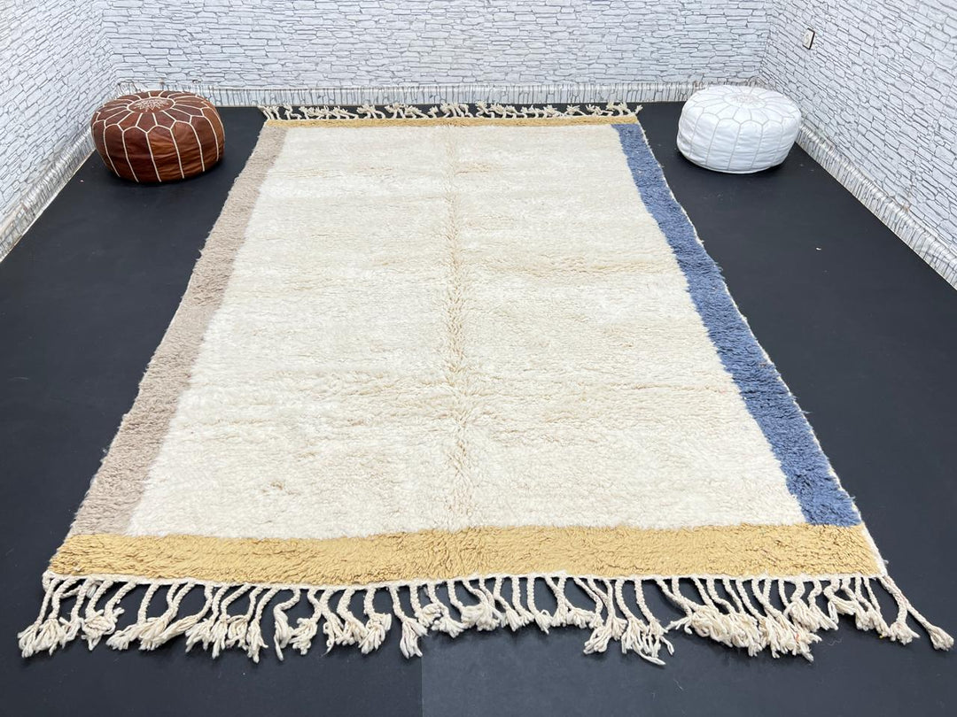 Handwoven neutral Moroccan wool rug with minimalist beige, mustard, and blue borders
