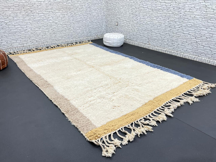 Handwoven neutral Moroccan wool rug with minimalist beige, mustard, and blue borders