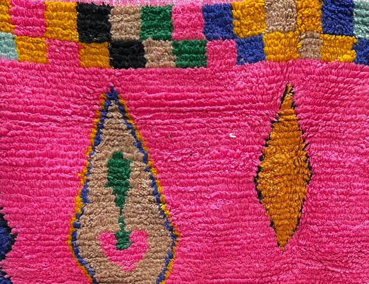 Handmade pink Moroccan runner rug with colorful geometric Berber motifs in green, blue, orange, yellow, and black.