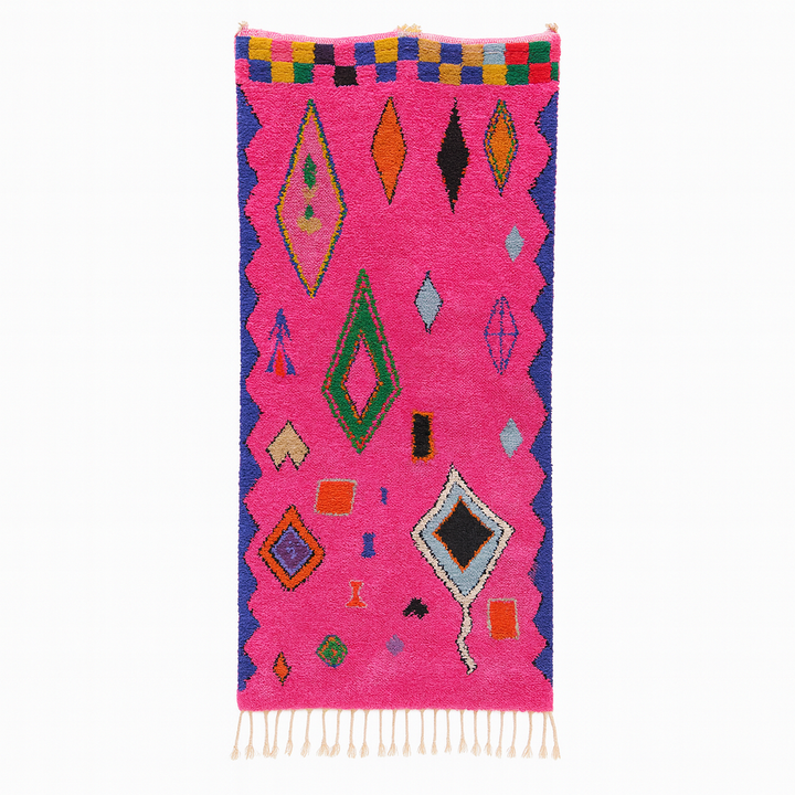 Handmade pink Moroccan runner rug with colorful geometric Berber motifs in green, blue, orange, yellow, and black.