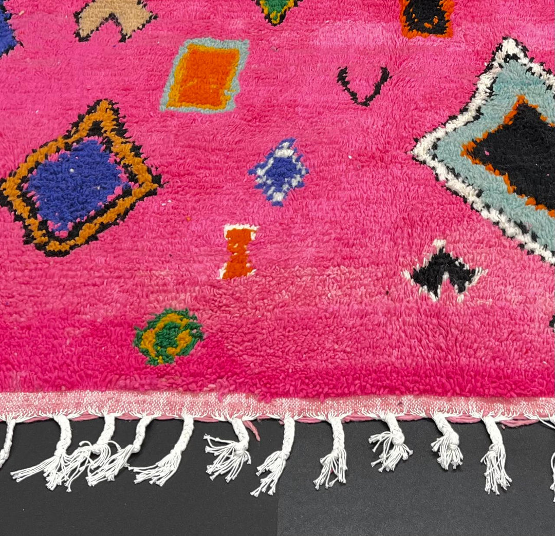 Handmade pink Moroccan runner rug with colorful geometric Berber motifs in green, blue, orange, yellow, and black.
