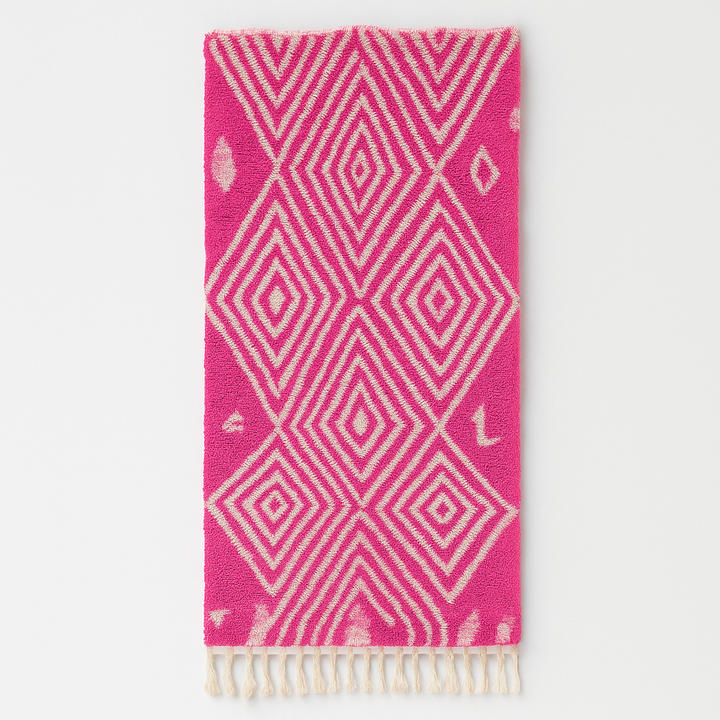 Pink Moroccan runner rug with geometric diamond pattern made of handmade wool and fringed edges on soft ivory background