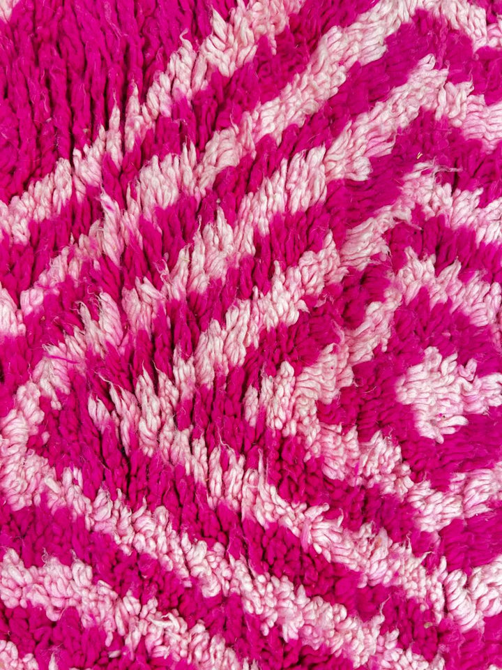 Pink Moroccan runner rug with geometric diamond pattern made of handmade wool and fringed edges on soft ivory background