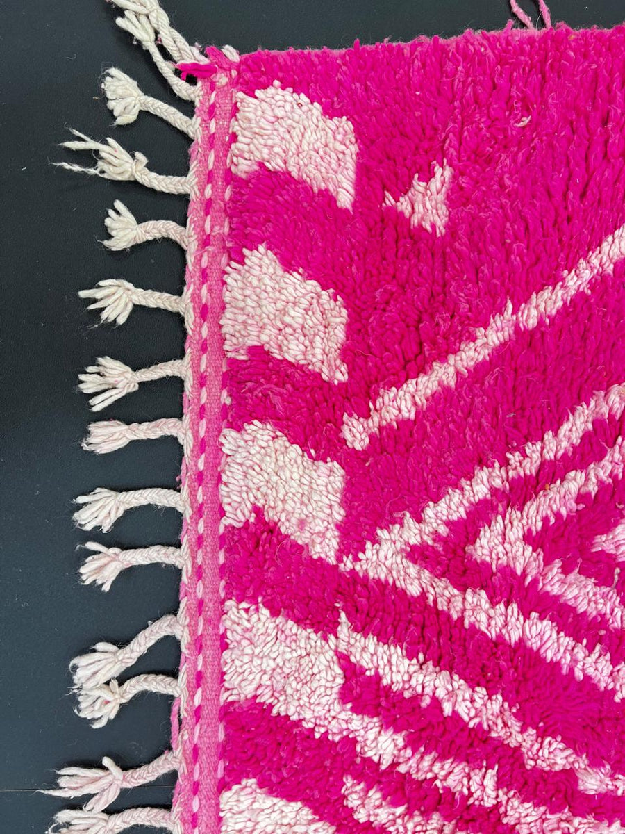 Pink Moroccan runner rug with geometric diamond pattern made of handmade wool and fringed edges on soft ivory background