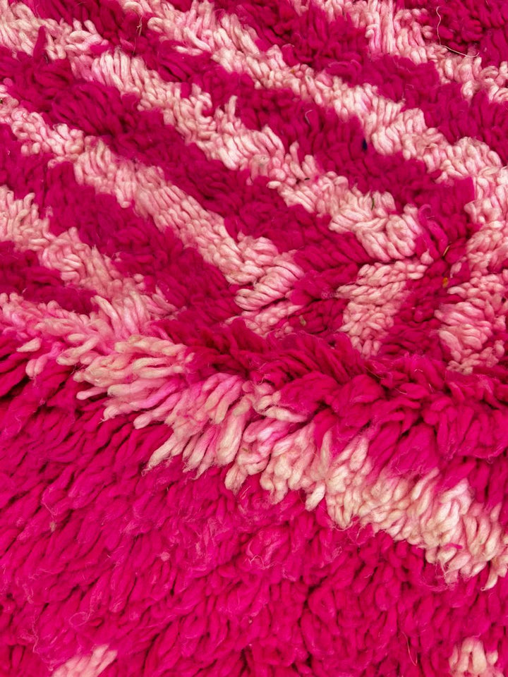 Pink Moroccan runner rug with geometric diamond pattern made of handmade wool and fringed edges on soft ivory background
