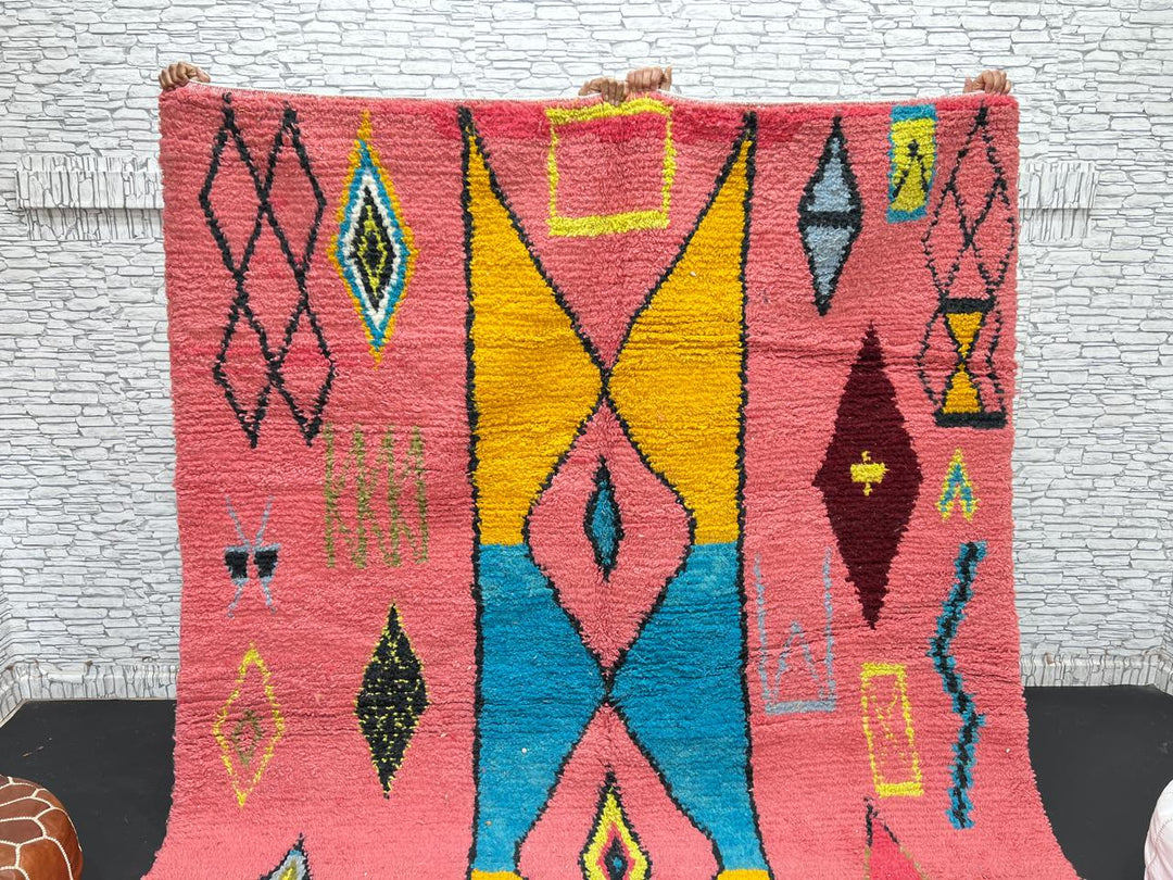 Handwoven pink Moroccan wool rug with colorful abstract geometric Berber design