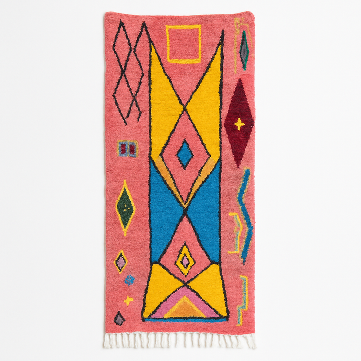 Handmade pink Moroccan wool runner rug with colorful geometric Berber motifs in yellow, turquoise, burgundy, and black