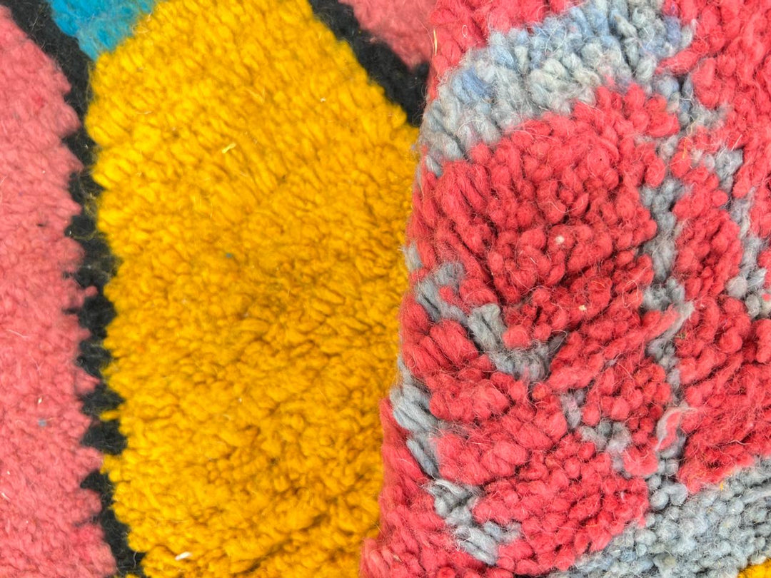 Handmade pink Moroccan wool runner rug with colorful geometric Berber motifs in yellow, turquoise, burgundy, and black