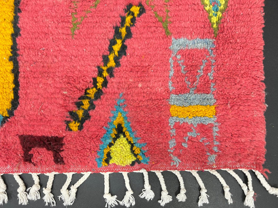 Handmade pink Moroccan wool runner rug with colorful geometric Berber motifs in yellow, turquoise, burgundy, and black