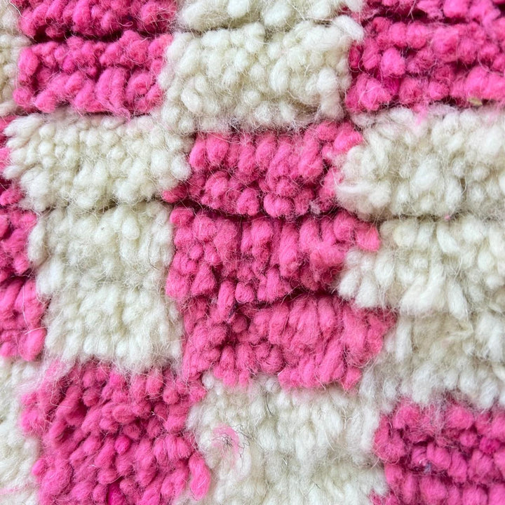 Handmade round Moroccan wool rug with pink and white checkerboard pattern and plush shag texture