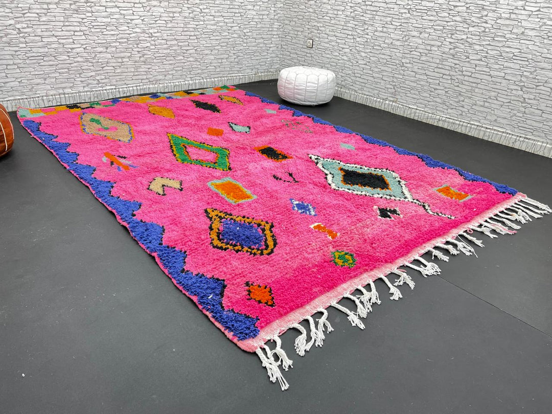 Vibrant pink Moroccan wool rug with colorful Berber motifs. 100% handmade, natural wool, and ethically crafted in Morocco.