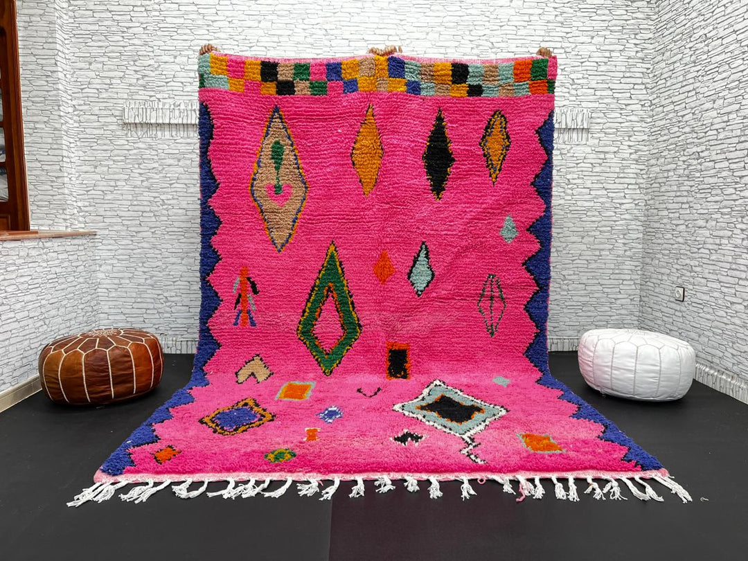 Vibrant pink Moroccan wool rug with colorful Berber motifs. 100% handmade, natural wool, and ethically crafted in Morocco.