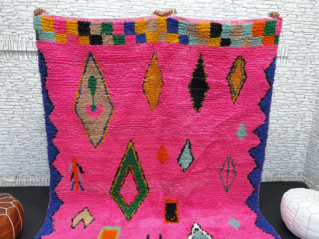 Vibrant pink Moroccan wool rug with colorful Berber motifs. 100% handmade, natural wool, and ethically crafted in Morocco.