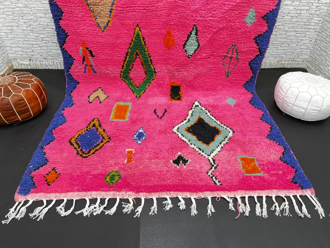 Vibrant pink Moroccan wool rug with colorful Berber motifs. 100% handmade, natural wool, and ethically crafted in Morocco.
