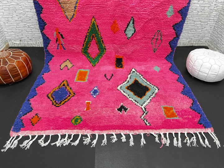 Vibrant pink Moroccan wool rug with colorful Berber motifs. 100% handmade, natural wool, and ethically crafted in Morocco.