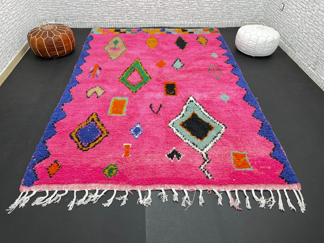 Vibrant pink Moroccan wool rug with colorful Berber motifs. 100% handmade, natural wool, and ethically crafted in Morocco.