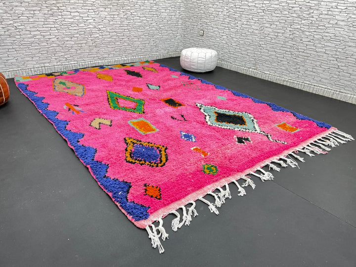 Vibrant pink Moroccan wool rug with colorful Berber motifs. 100% handmade, natural wool, and ethically crafted in Morocco.