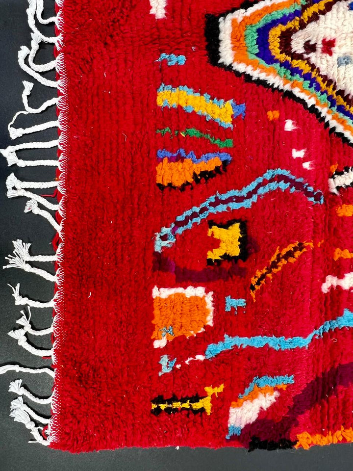 Handwoven red Moroccan wool runner rug with colorful Berber tribal patterns