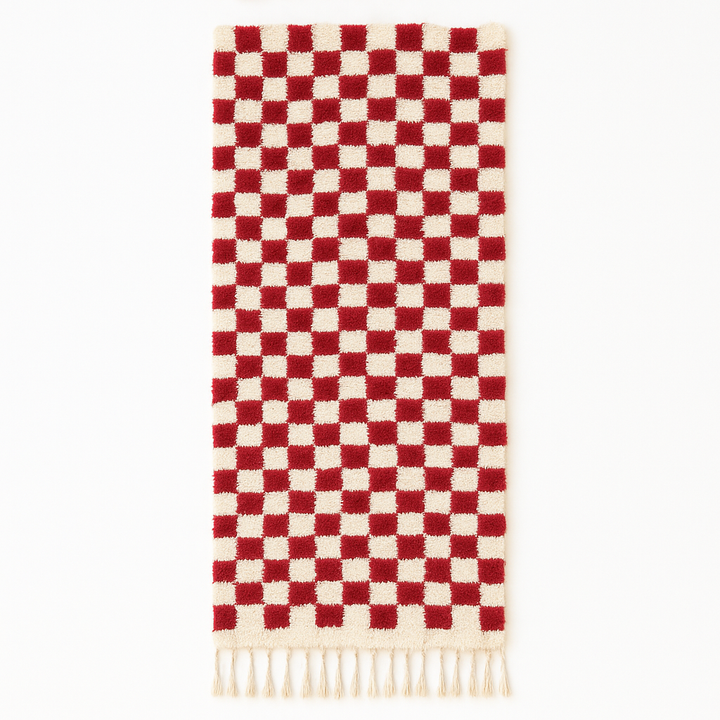Red and white checkerboard Moroccan runner rug made of handmade wool with fringed ends on white background 