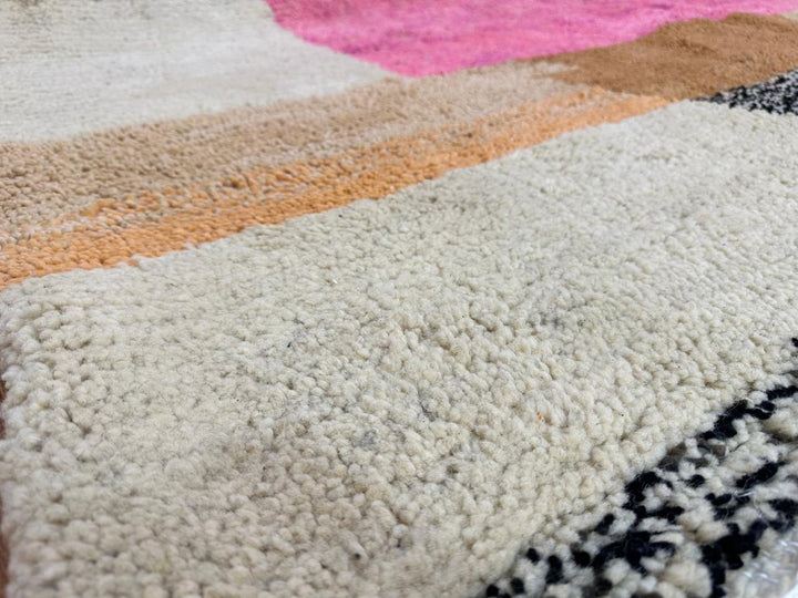 Round handmade Moroccan wool rug with abstract artistic design in pink, blue, caramel and neutral tones