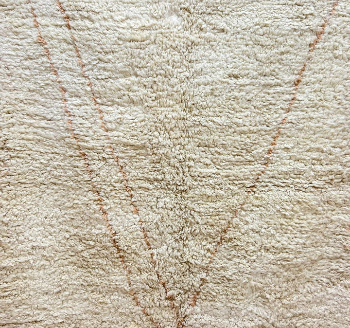 Round handmade Moroccan wool shag rug in cream with subtle Beni Ourain cross pattern on white background