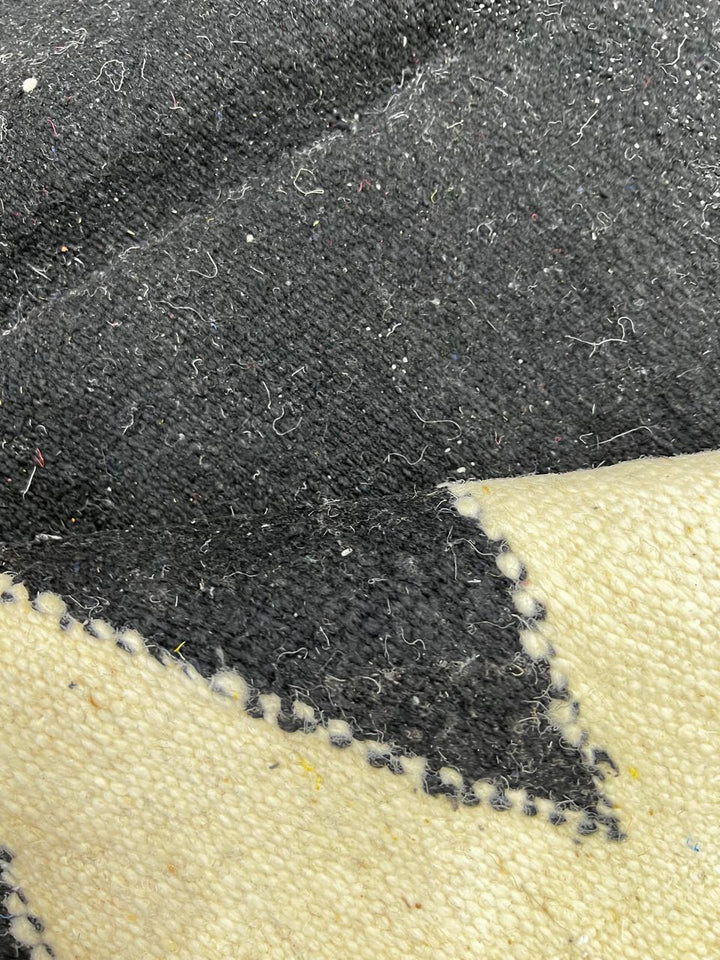 Handmade round Moroccan flatweave kilim rug with black and white zigzag geometric pattern, woven from natural wool.