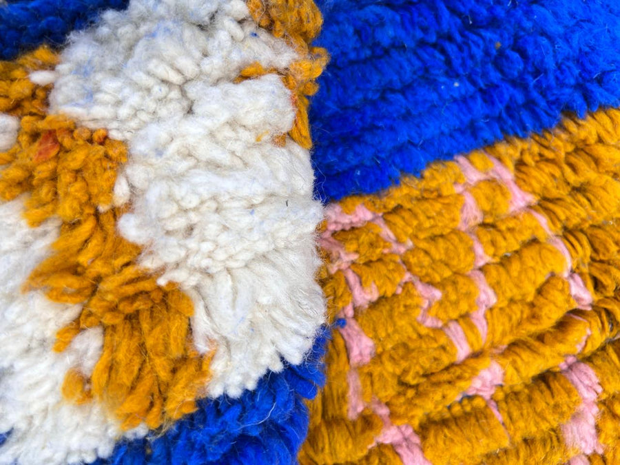 Round blue Moroccan Berber wool rug with colorful geometric patterns on a white background