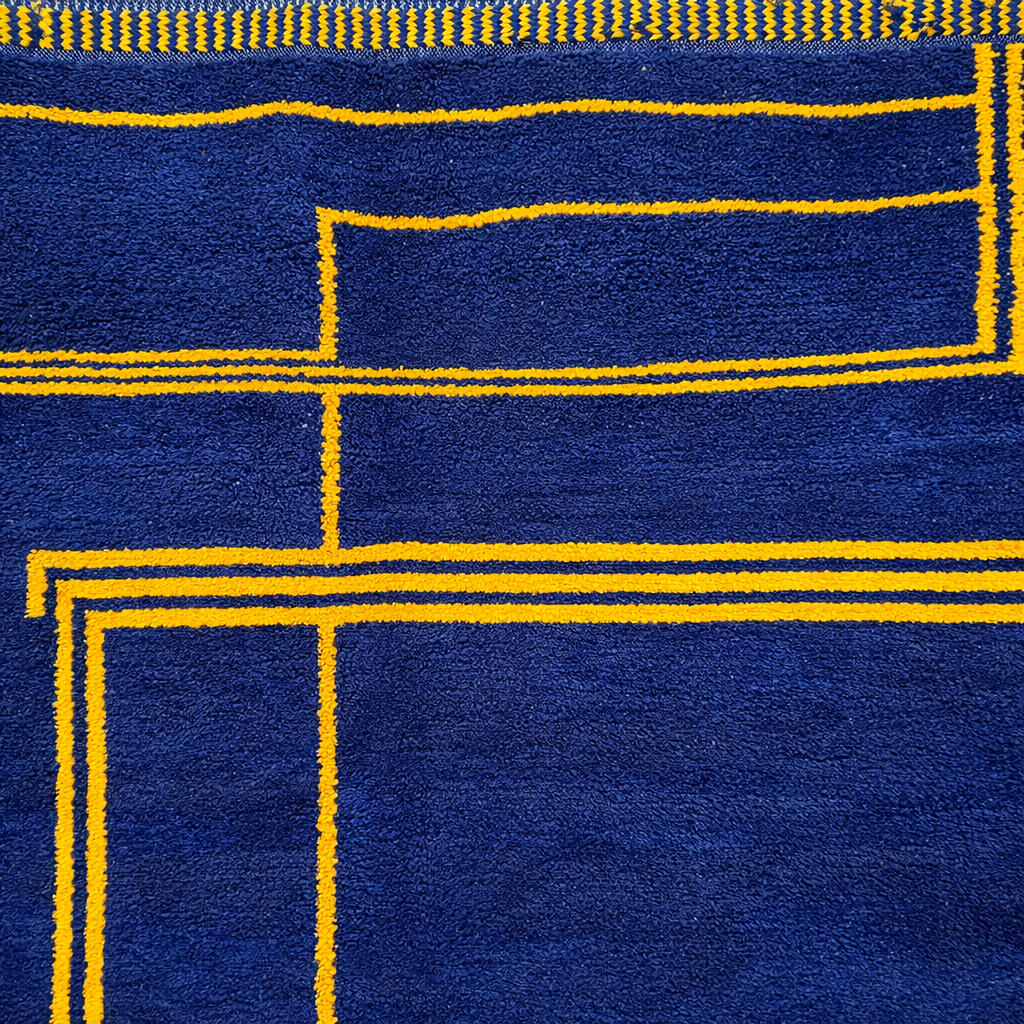 Round navy blue Moroccan wool rug with mustard yellow geometric Berber pattern, handmade artisan round carpet on white background