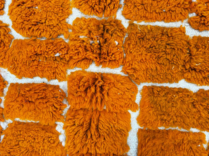 Round orange Moroccan wool shag rug with textured handwoven pattern on white background