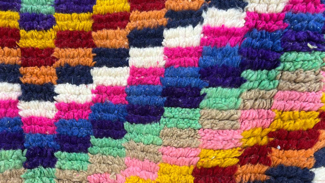 Round colorful Moroccan wool rug with abstract Berber pattern in pink, blue, green, yellow and ivory tones