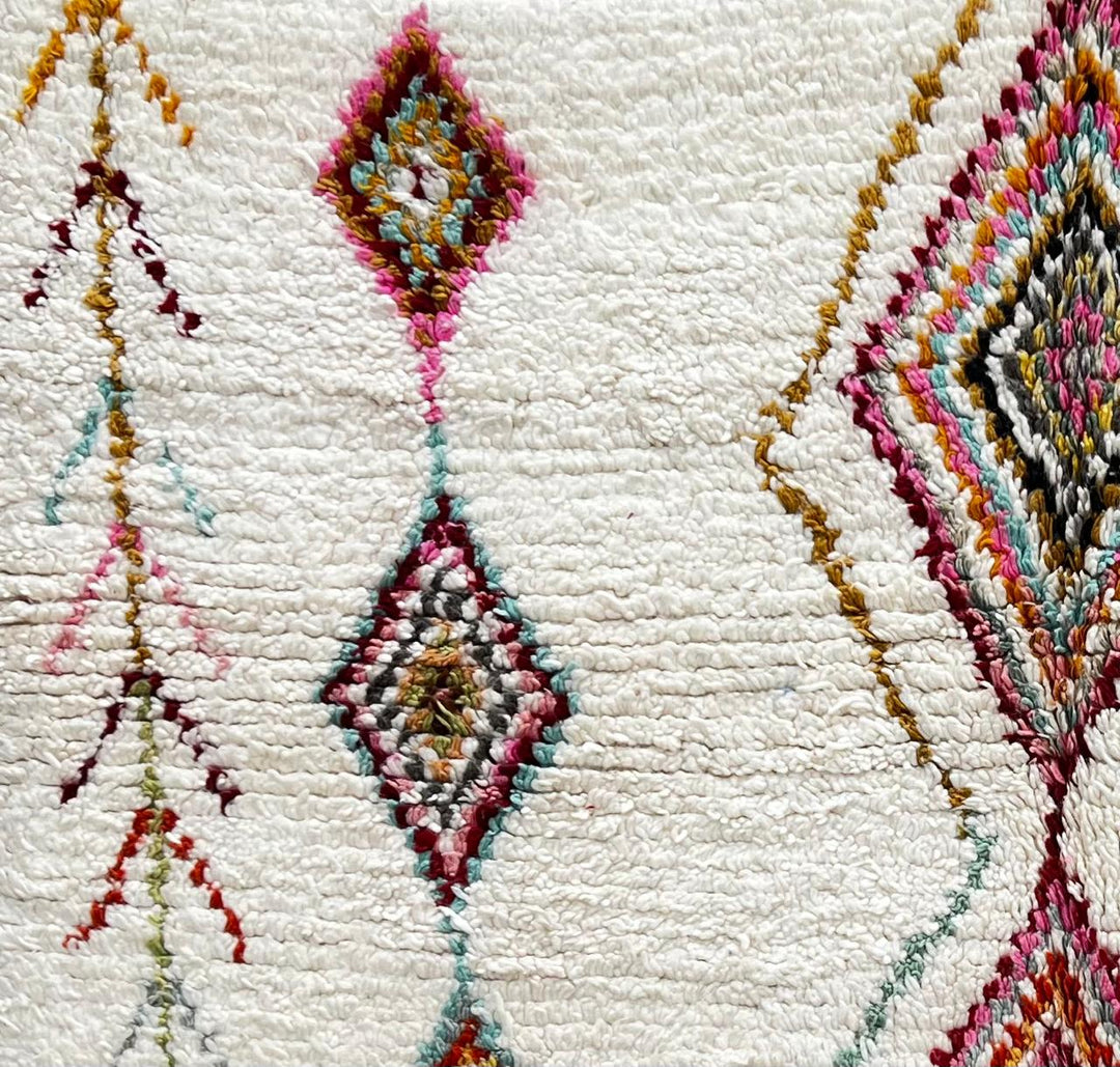 Round white Moroccan wool rug with colorful diamond and tribal line motifs handmade by Berber artisans
