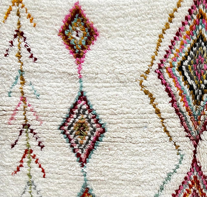 Round white Moroccan wool rug with colorful diamond and tribal line motifs handmade by Berber artisans
