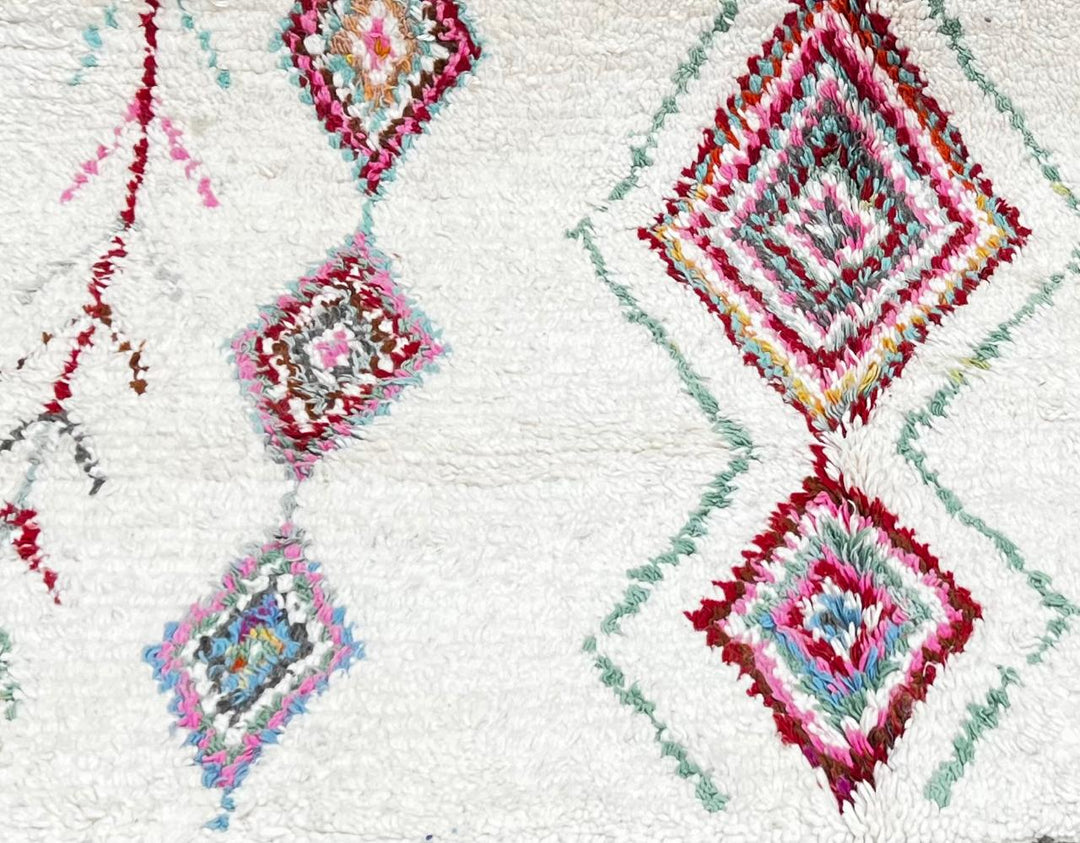 Round white Moroccan wool rug with colorful diamond and tribal line motifs handmade by Berber artisans