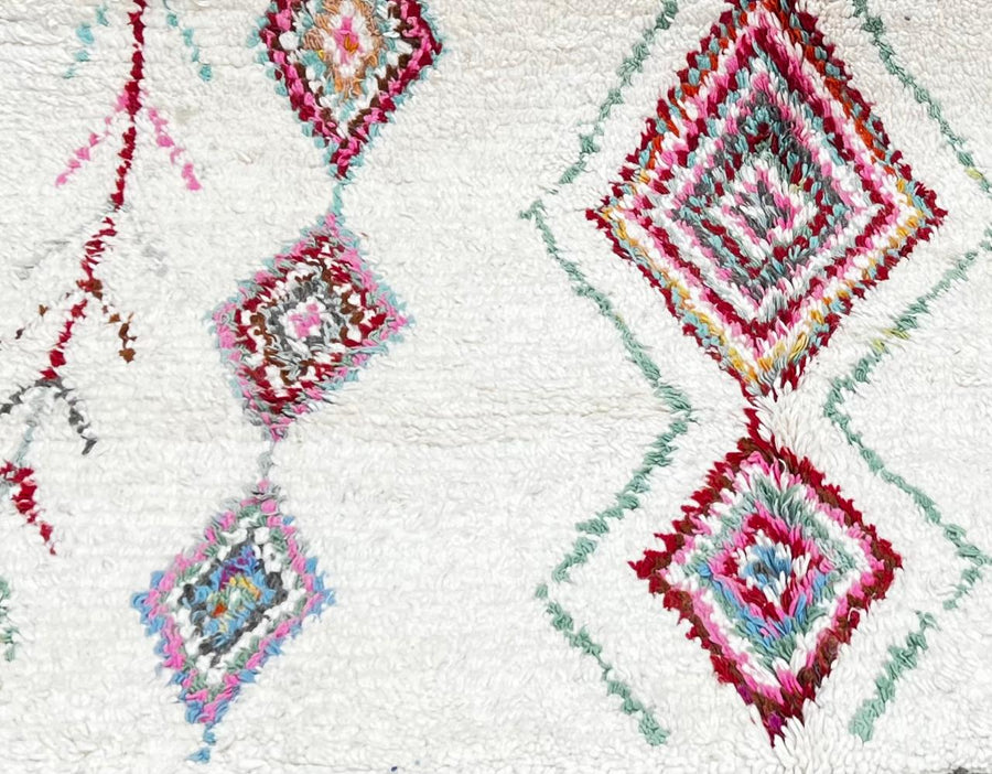 Round white Moroccan wool rug with colorful diamond and tribal line motifs handmade by Berber artisans