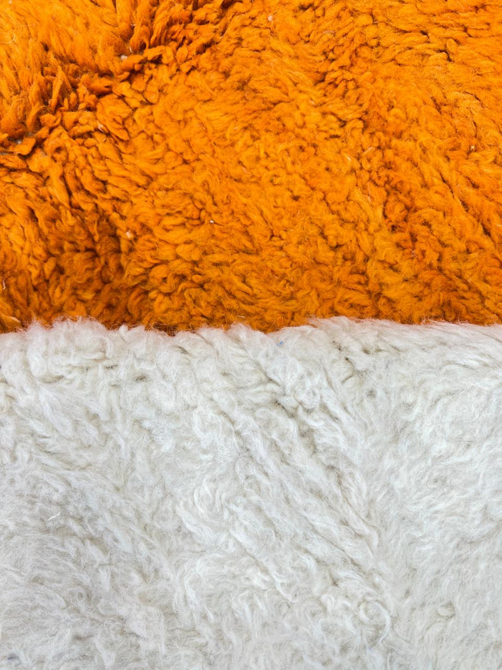 Round modern Moroccan rug with abstract orange, red, yellow, and white geometric design