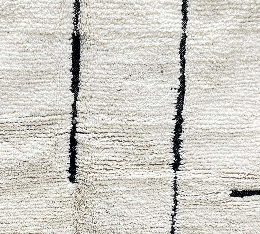 Round Moroccan rug with minimalist black abstract line pattern on a cream-white wool base